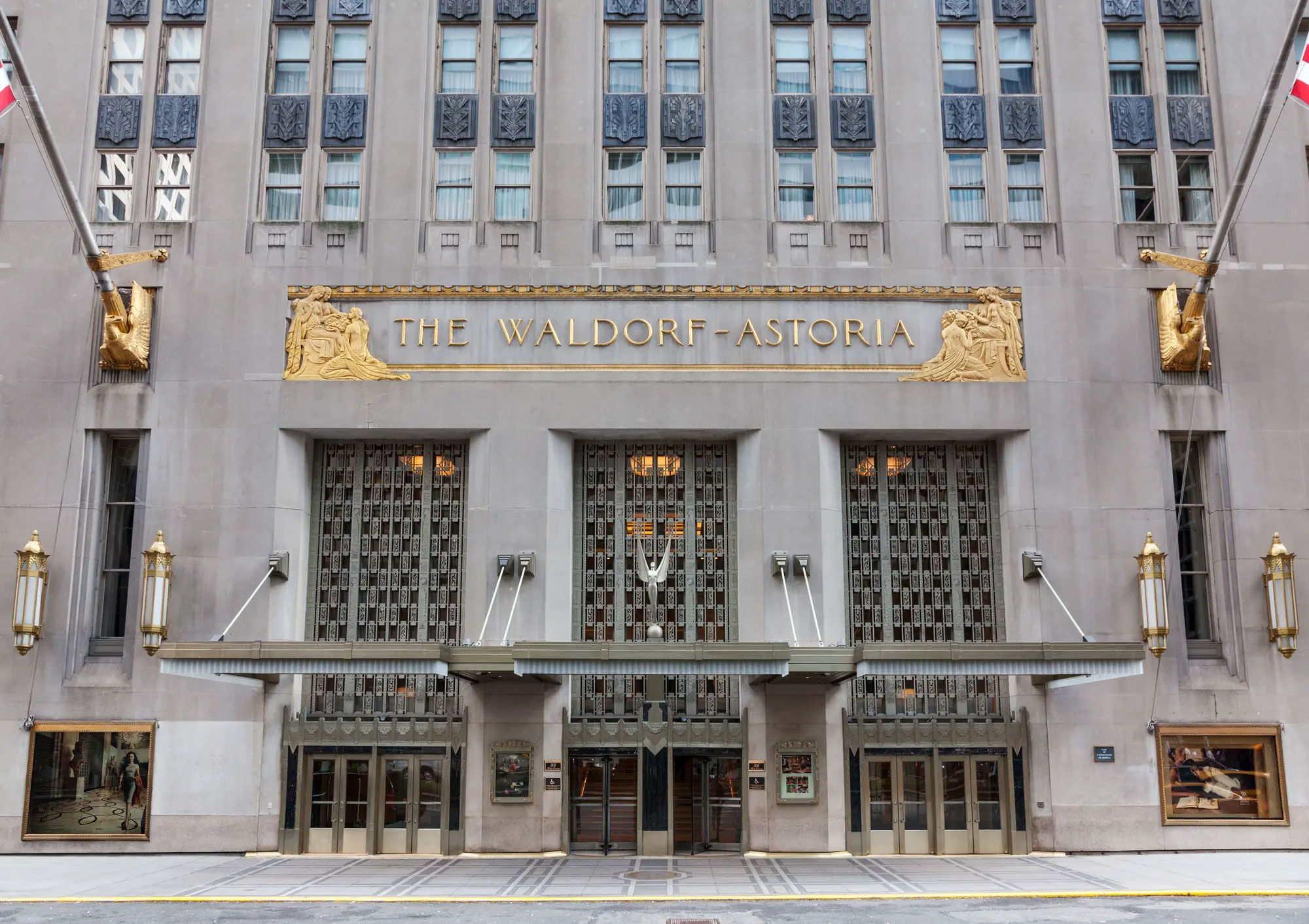 Facade of The Waldorf-Astoria hotel with gold lettering and decorative gold sculptures above the entrance.