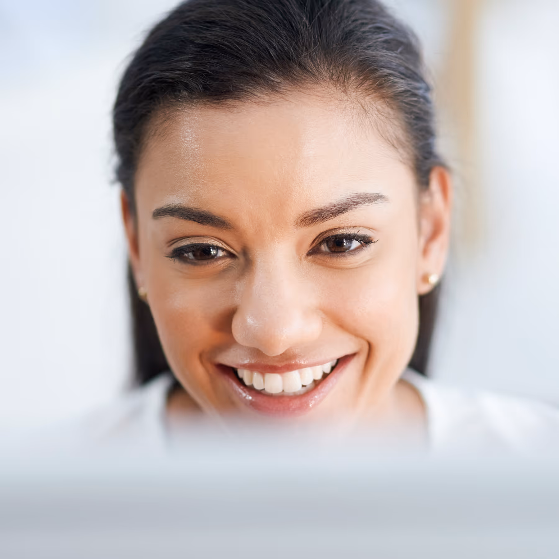 Close-up of a happy woman smiling while looking at her computer.