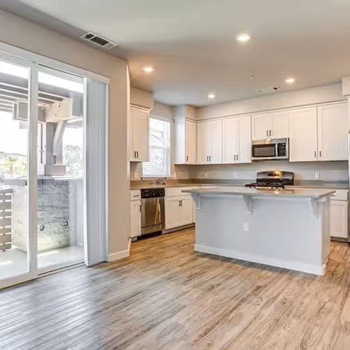 Kitchen with island, white cabinets, and stainless steel appliances featuring view of patio doors