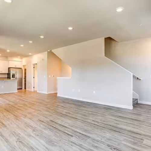 Unfurnished living area with view of kitchen and stairs to second floor