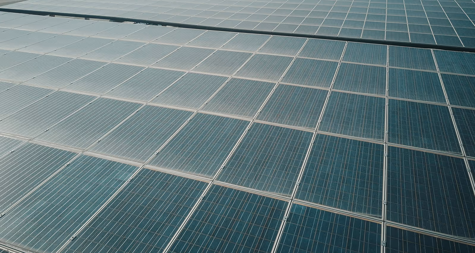 Aerial view of a large array of blue solar panels arranged in a grid formation.