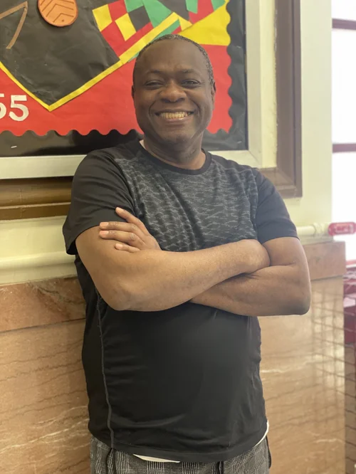 Smiling custodial staff member standing in school hallway