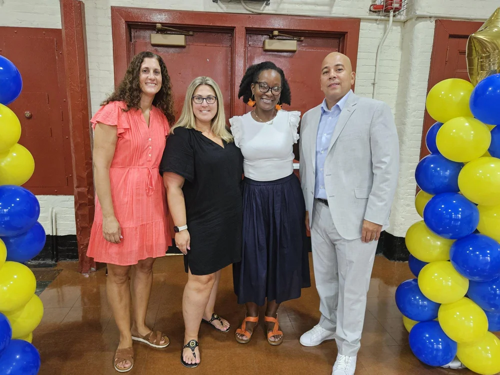 Four school staff members posing together at a school celebration event