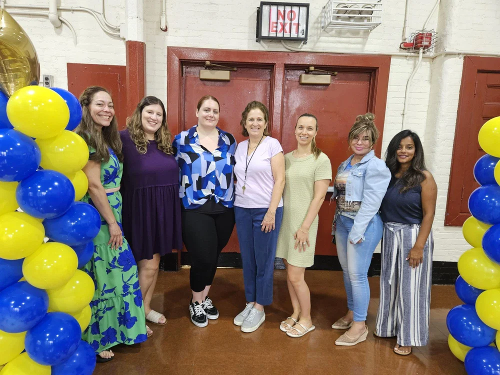 Seven staff members posing together at a school celebration event