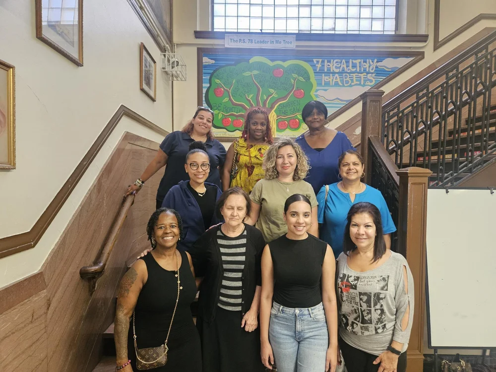 PS 78 paraprofessional staff posing together on school staircase