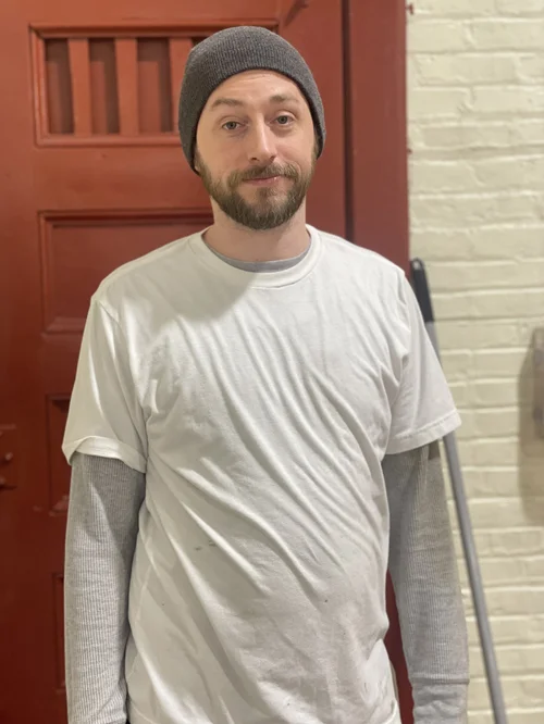 Male custodial staff member standing near school entrance door