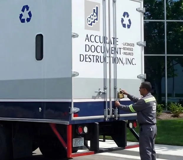 Uniformed technician locking the rear doors of an Accurate Document Destruction, Inc. truck.