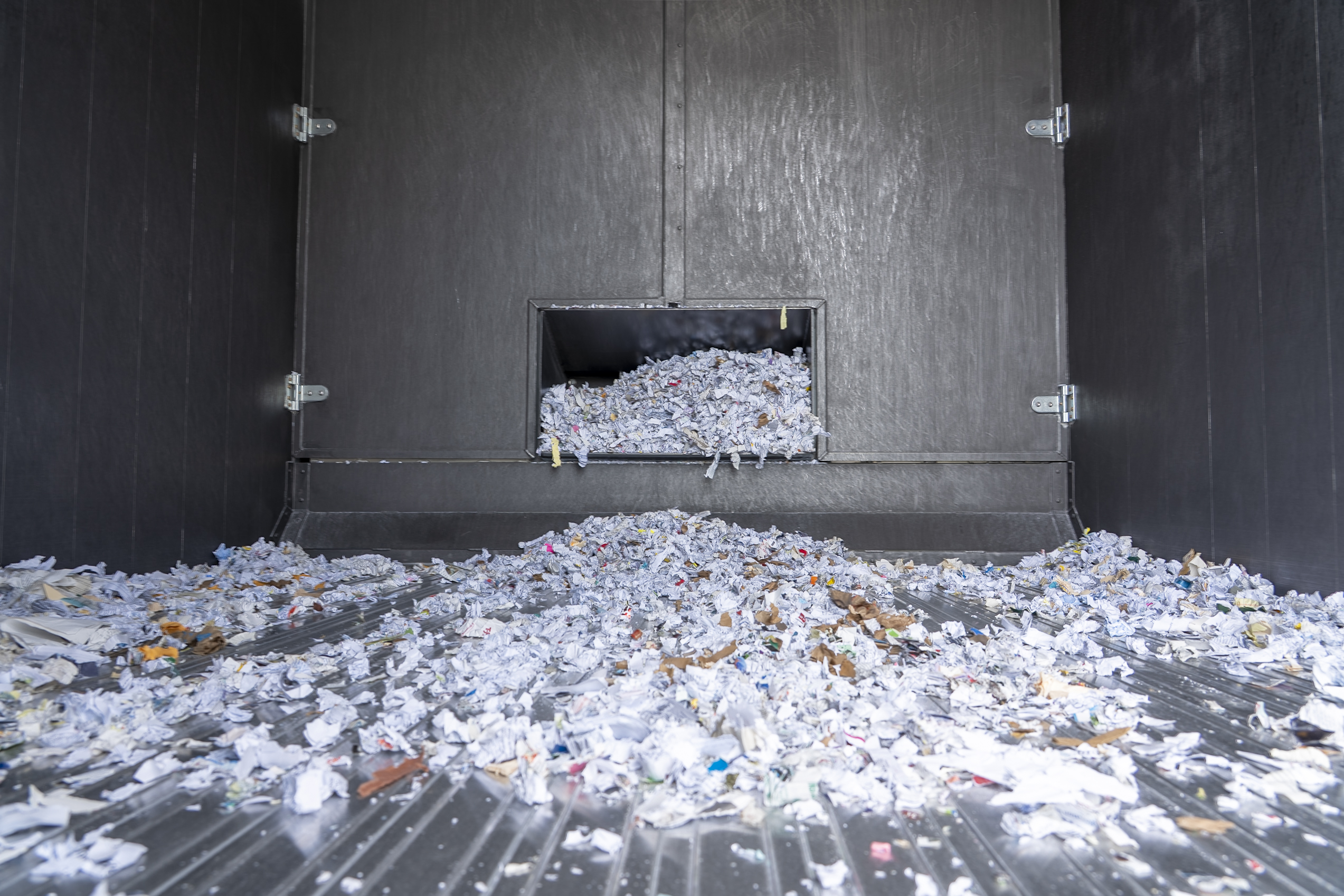 Pile of shredded paper scattered inside a large industrial machine compartment.