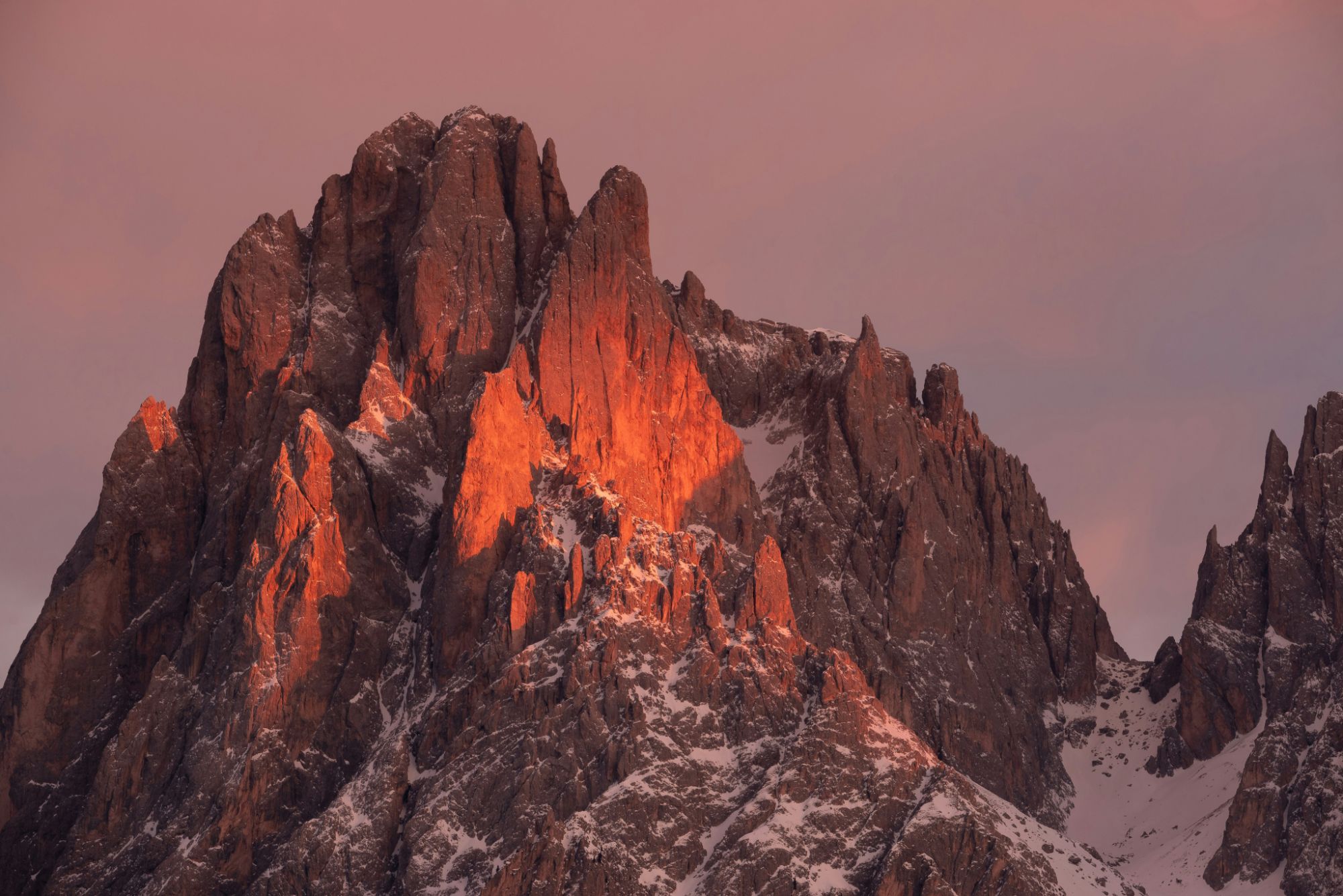 Snow-capped rocky summit lit by the setting sun
