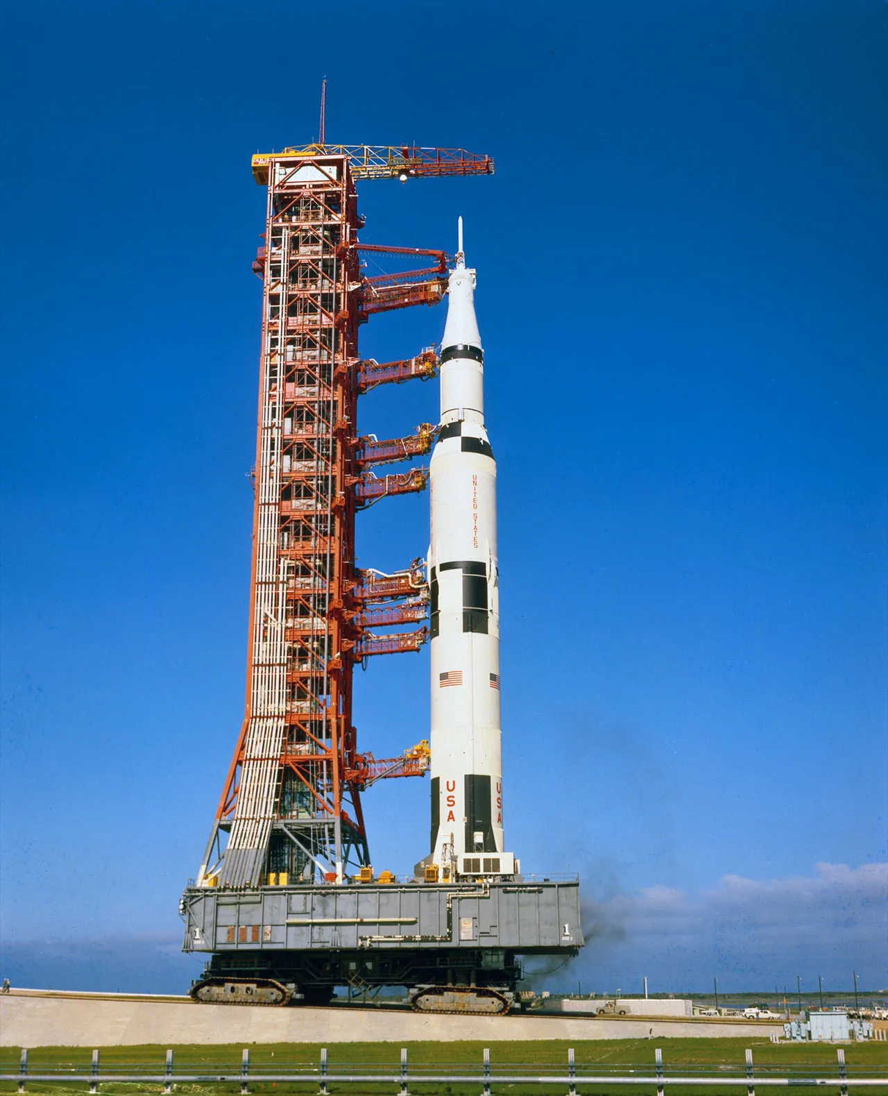 Saturn V rocket on mobile launch platform with blue sky background at Kennedy Space Center.