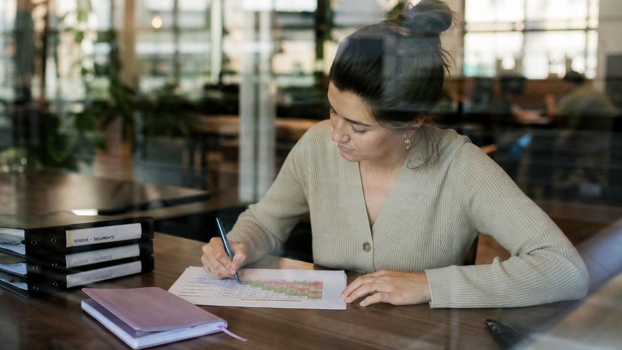A professional woman reviews a risk assessment chart while working at her desk in an office setting.