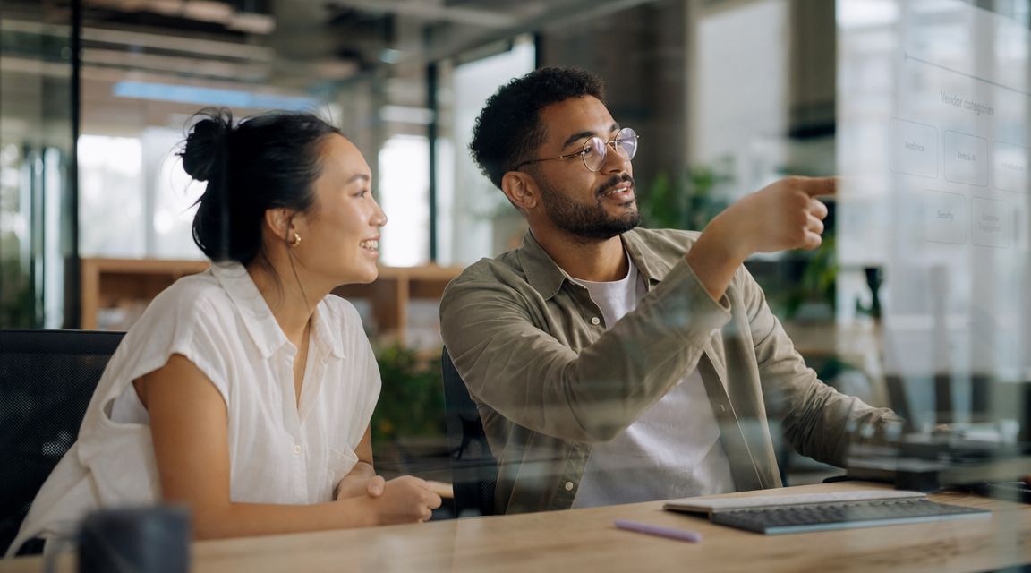A diverse man and woman collaborating on a software asset management project at an office desk.
