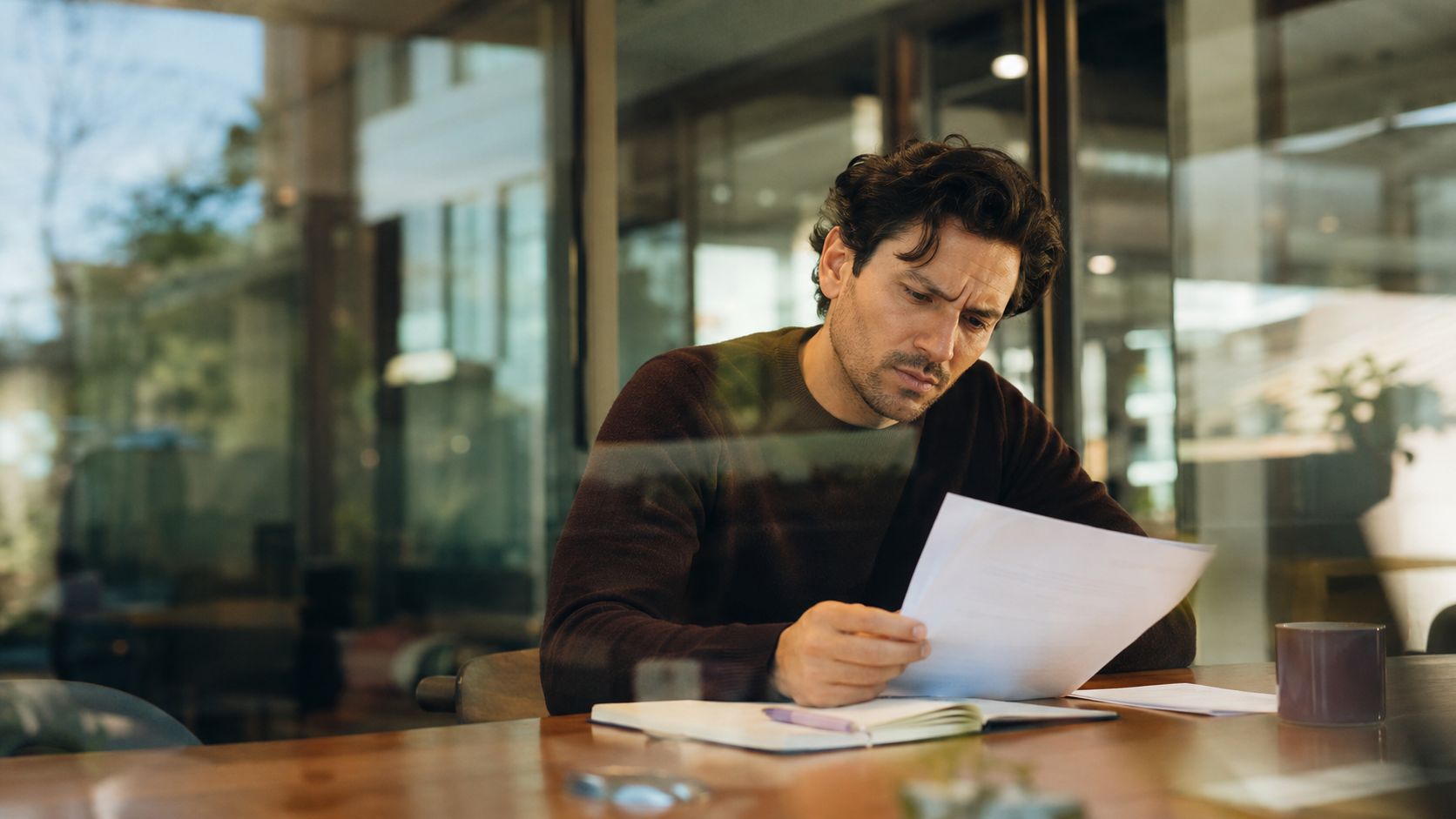 A focused man sitting at a desk reviewing important documents in a professional office environment.
