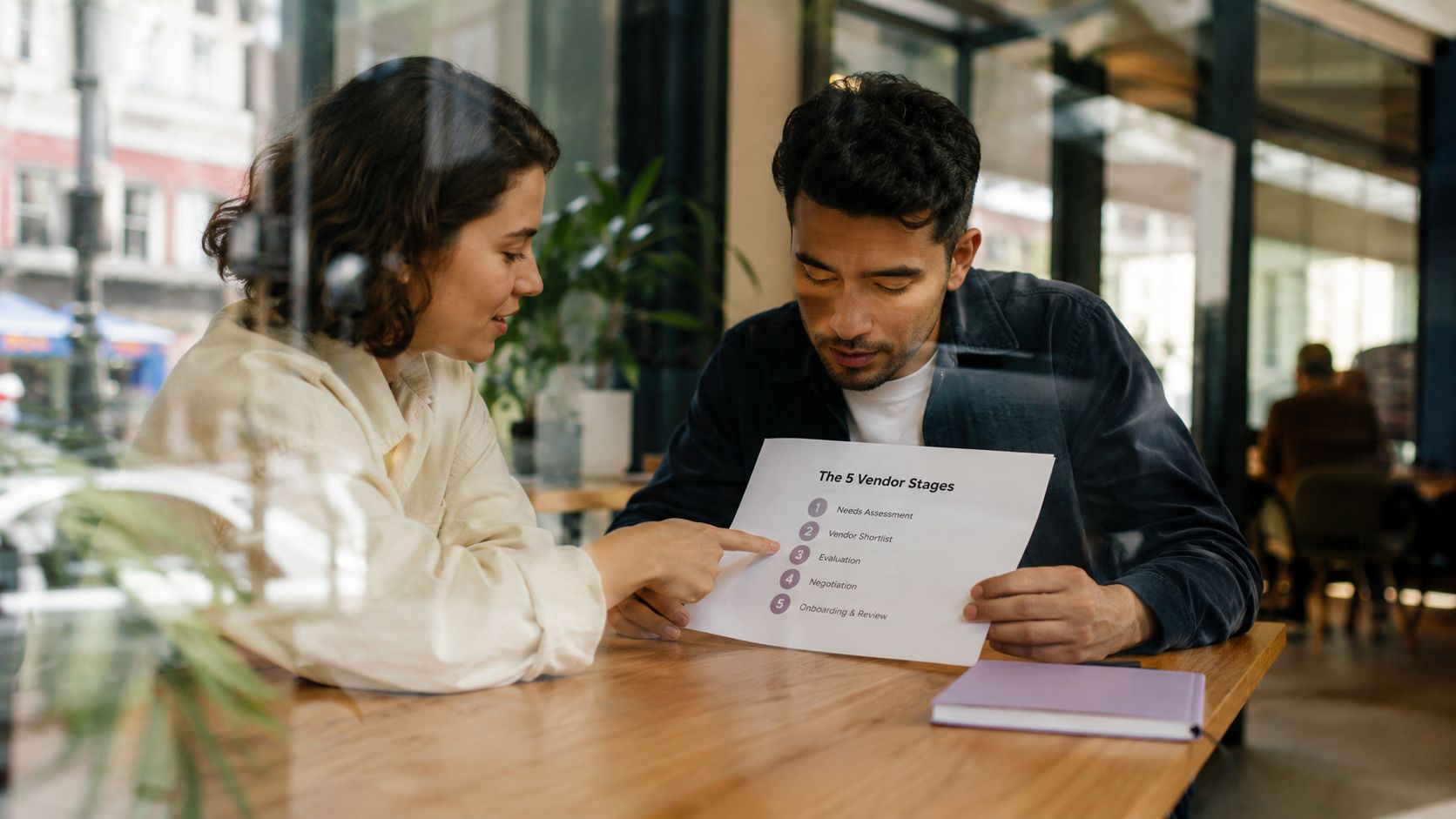 A woman and a man discussing the five vendor stages on a printed document at a table.