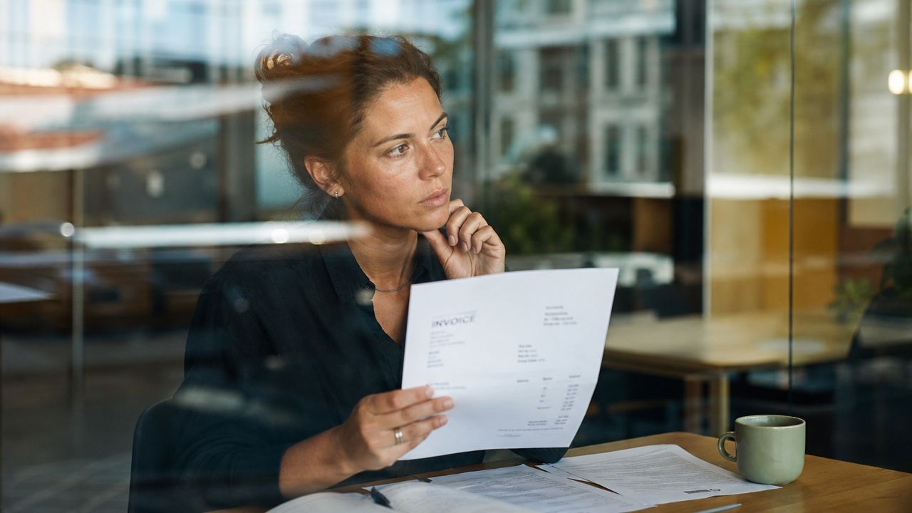 A focused woman reviewing an invoice at her desk, symbolizing professional financial management in an office.