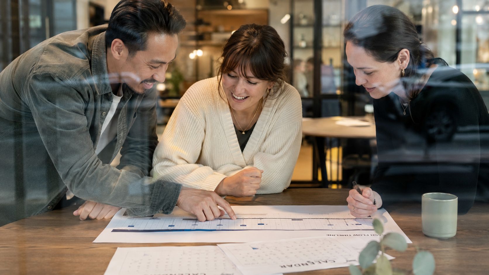 A diverse business team collaborating on a cash flow timeline and calendar in a modern office space.