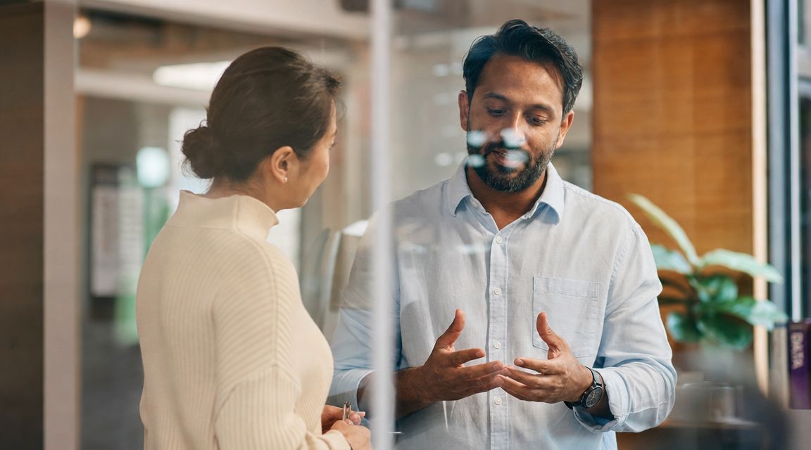 A professional man and woman having a collaborative discussion in a modern office environment.
