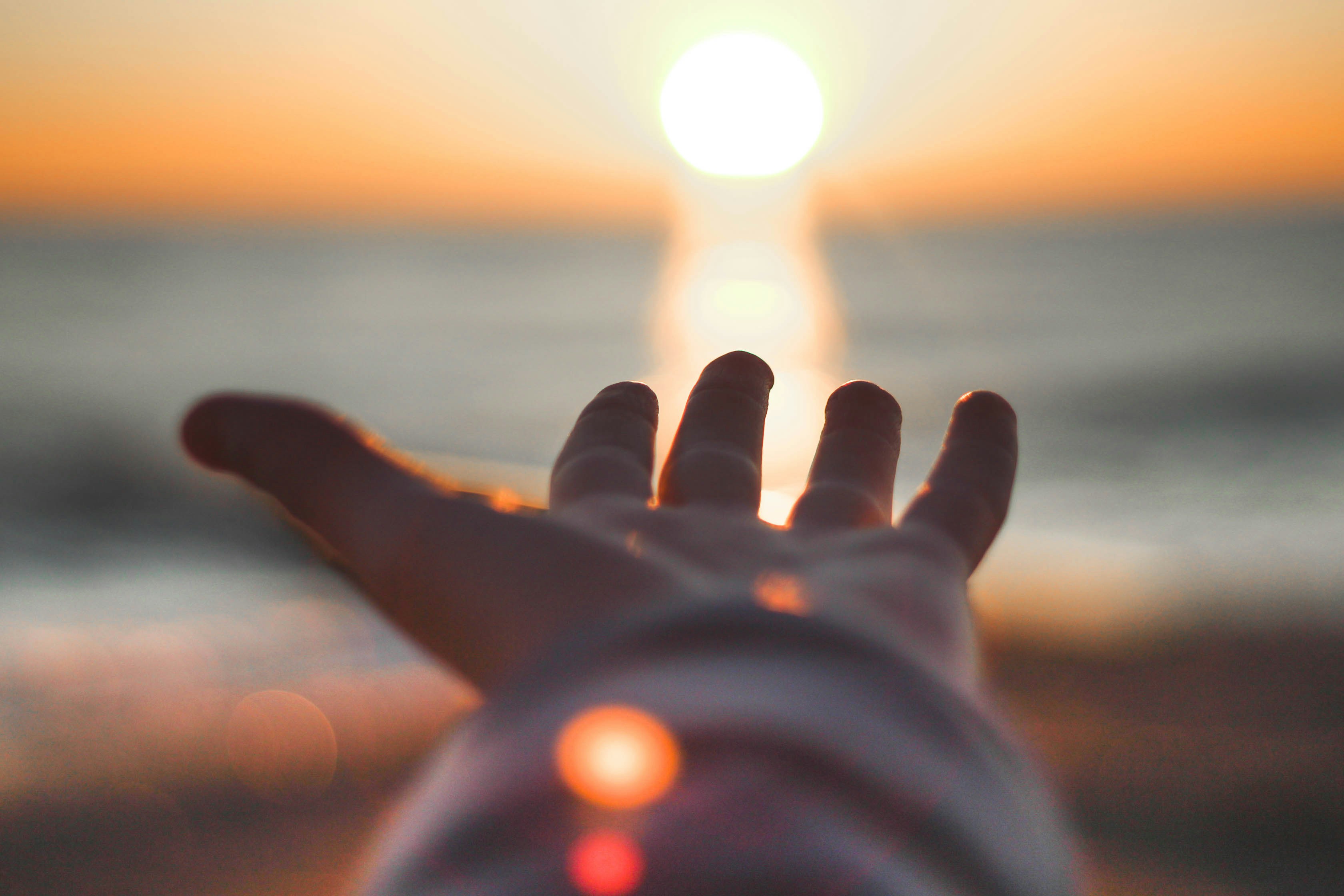 Main tendue vers le soleil couchant au-dessus de la mer
