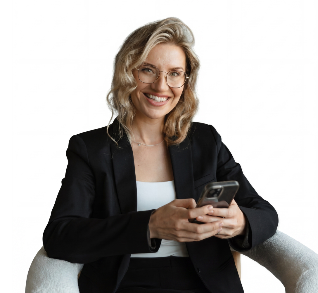 Smiling woman with glasses in black blazer sitting in chair holding a smartphone.