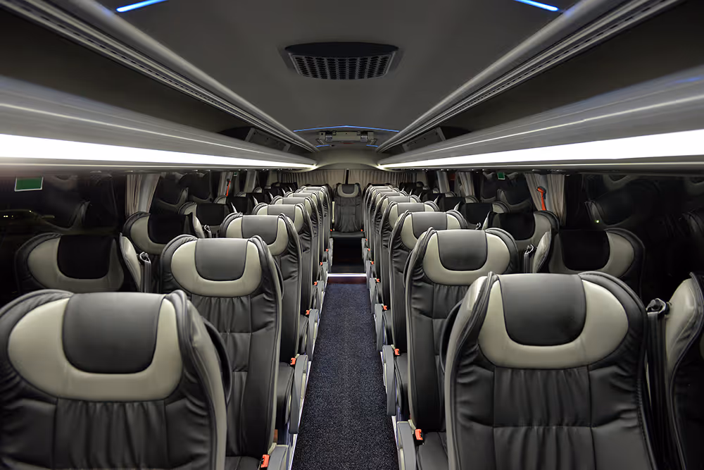 Interior view of a modern coach bus with black and gray leather seats arranged in rows along a central aisle.