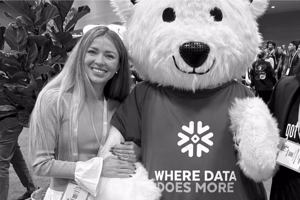 Smiling woman with long hair posing next to a person in a large white bear costume wearing a shirt that says 'WHERE DATA DOES MORE'.