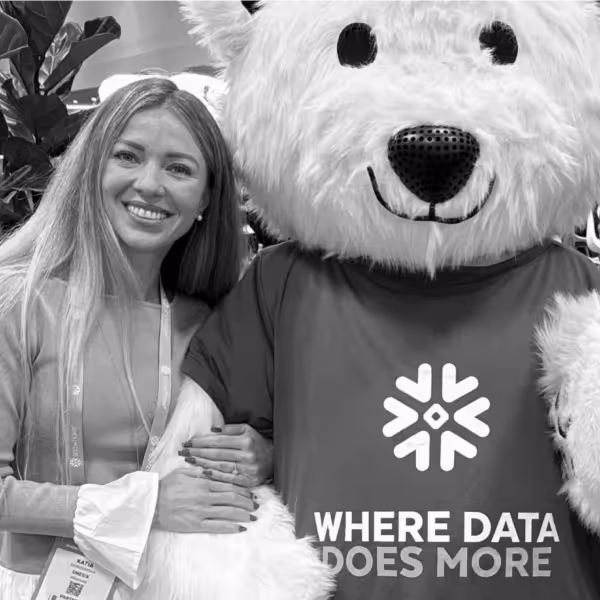 Smiling woman with long hair standing next to a person in a large white bear costume wearing a shirt that says 'WHERE DATA DOES MORE.'
