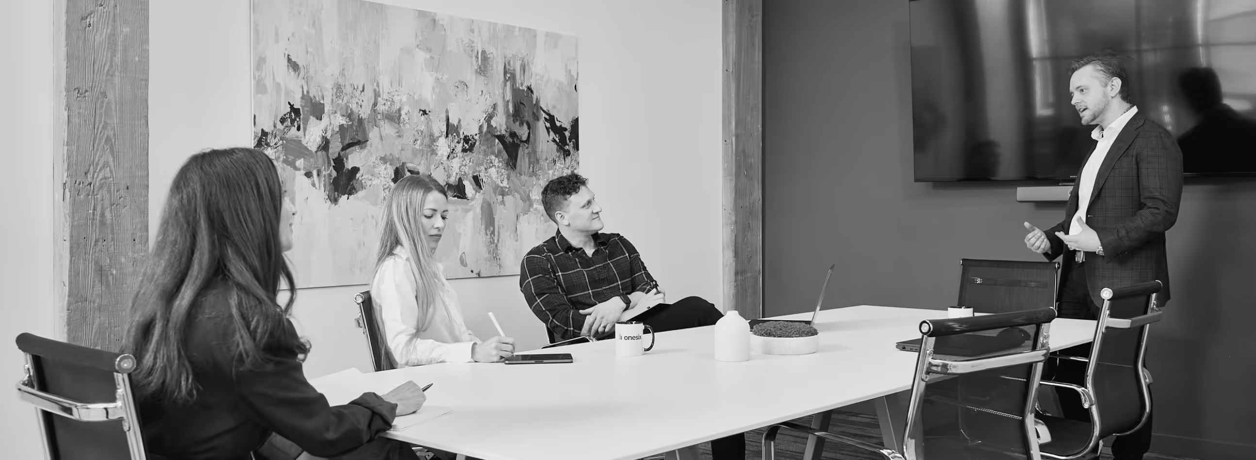 Businessman giving a presentation to three colleagues seated around a conference table in a modern office.