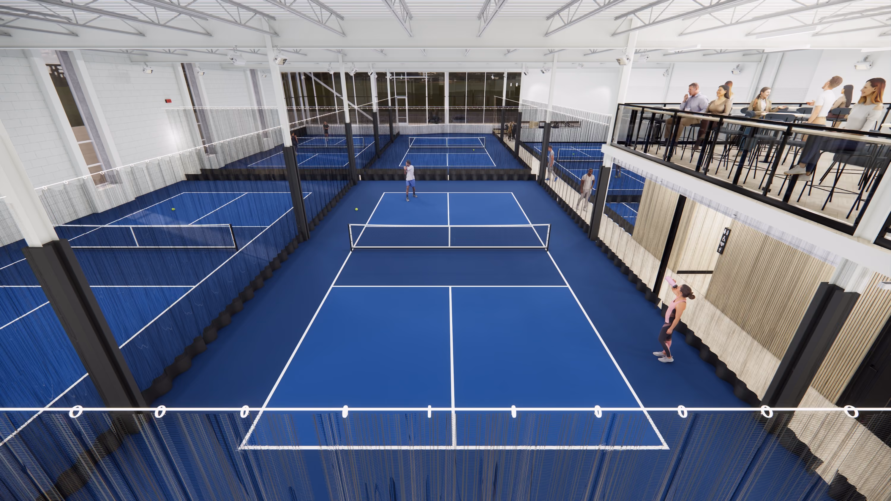 Indoor blue pickleball courts with players and spectators on an elevated seating area.