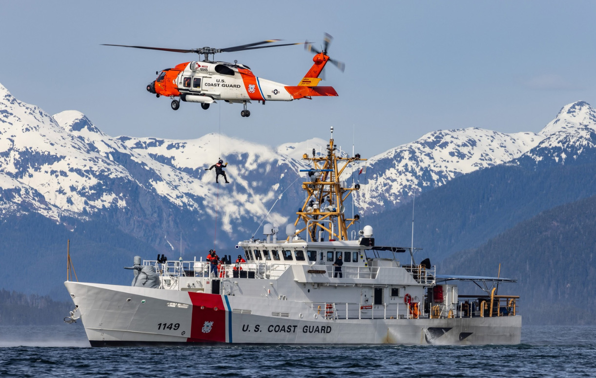 U.S. Coast Guard helicopter crew conducts a rescue hoist exercise above a Coast Guard cutter