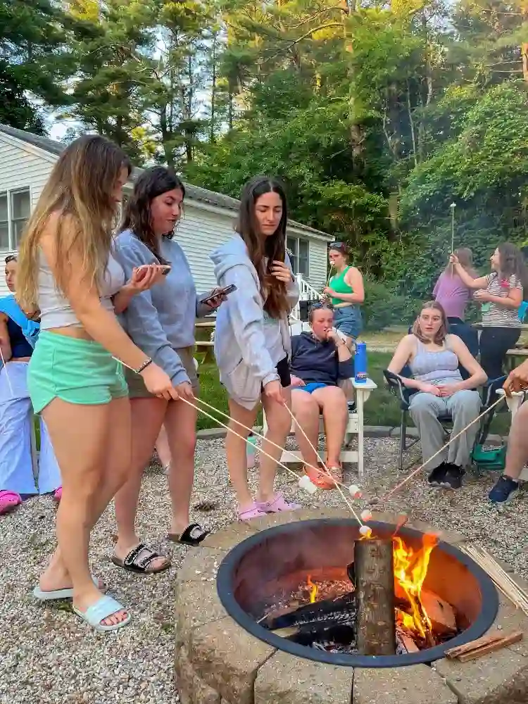 Camp counsellors roasting marshmallows at a firepit at a USA summer camp