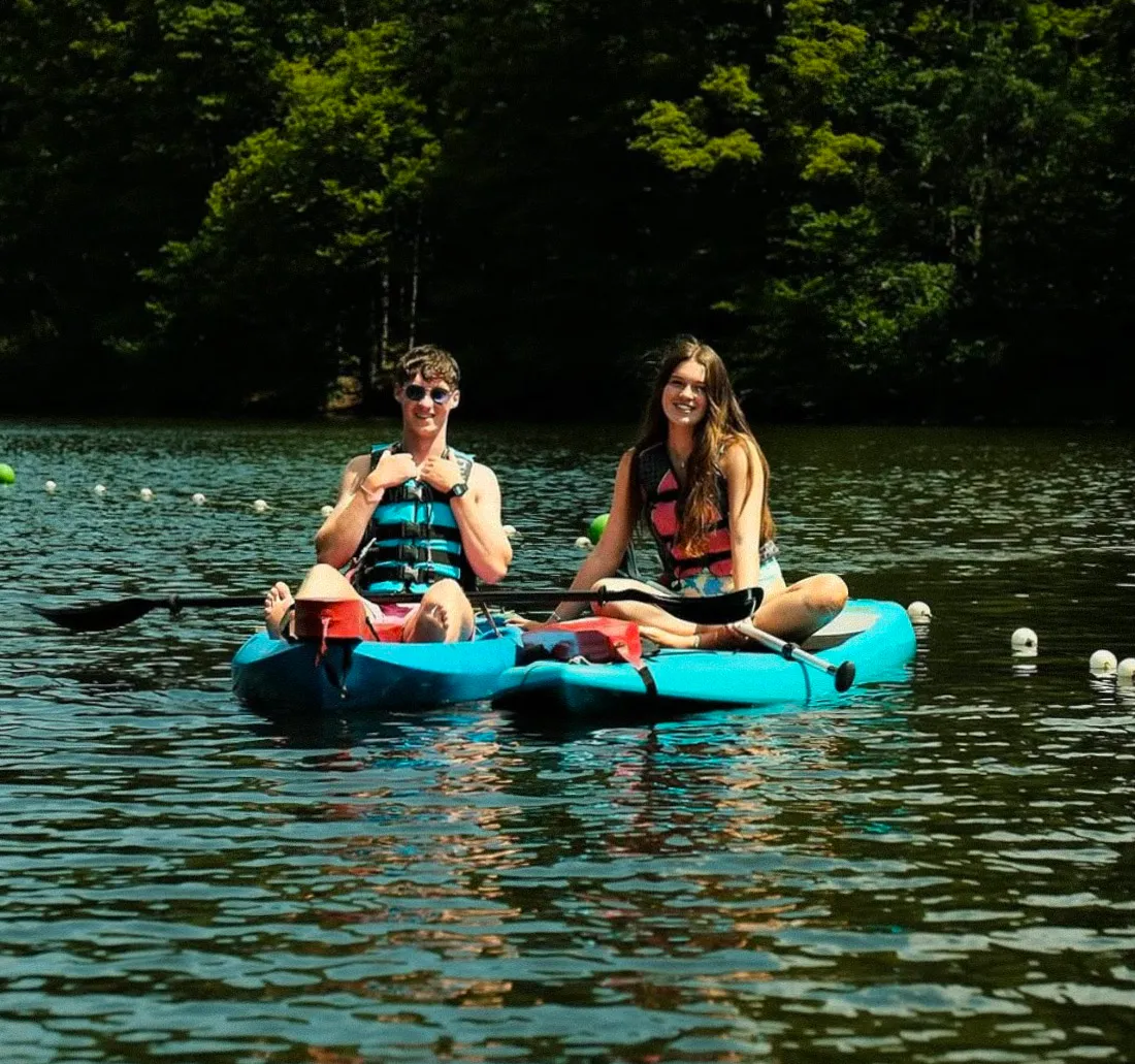 Two AmeriCamp counsellors kayaking on a lake at a USA summer camp.