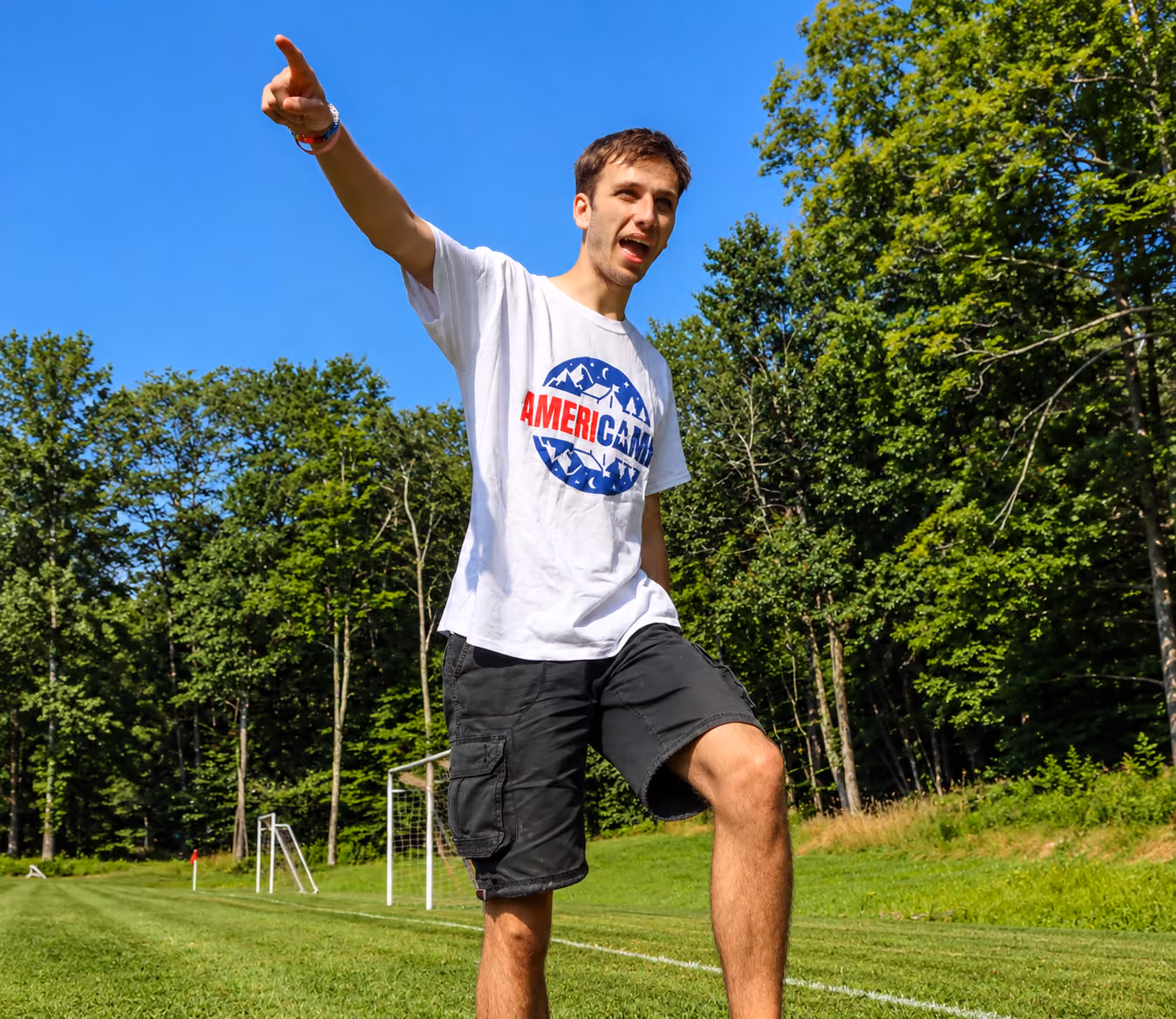 AmeriCamp summer camp counsellor pointing across an outdoor sports field in America.