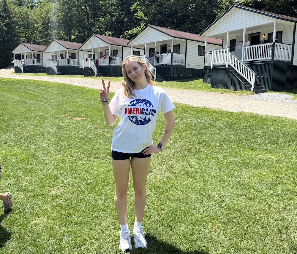 AmeriCamp Counsellor standing in front of cabins