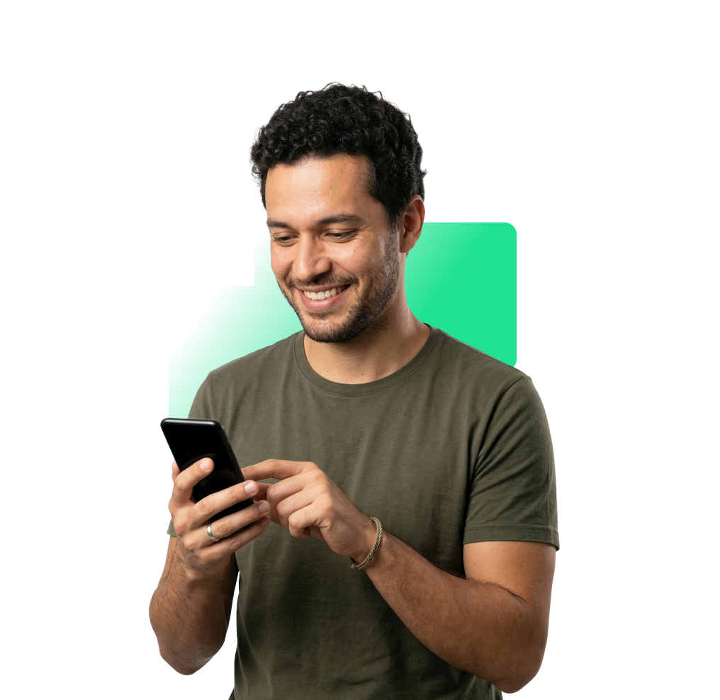 Smiling man with curly hair wearing olive shirt using a smartphone on green background.