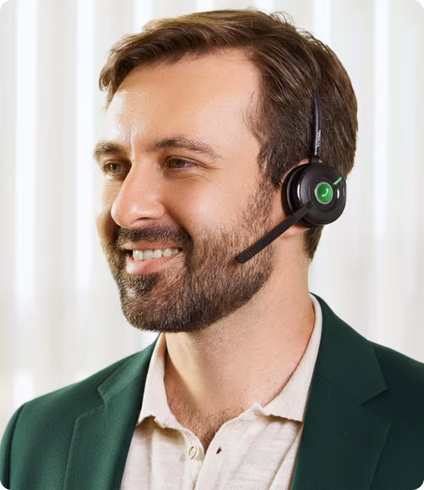 Smiling man with beard wearing a green jacket and headset with microphone.