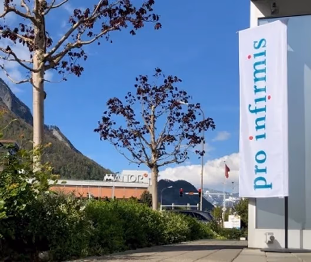 Outdoor scene with trees, mountain backdrop, and a white vertical banner reading 'pro informis'.