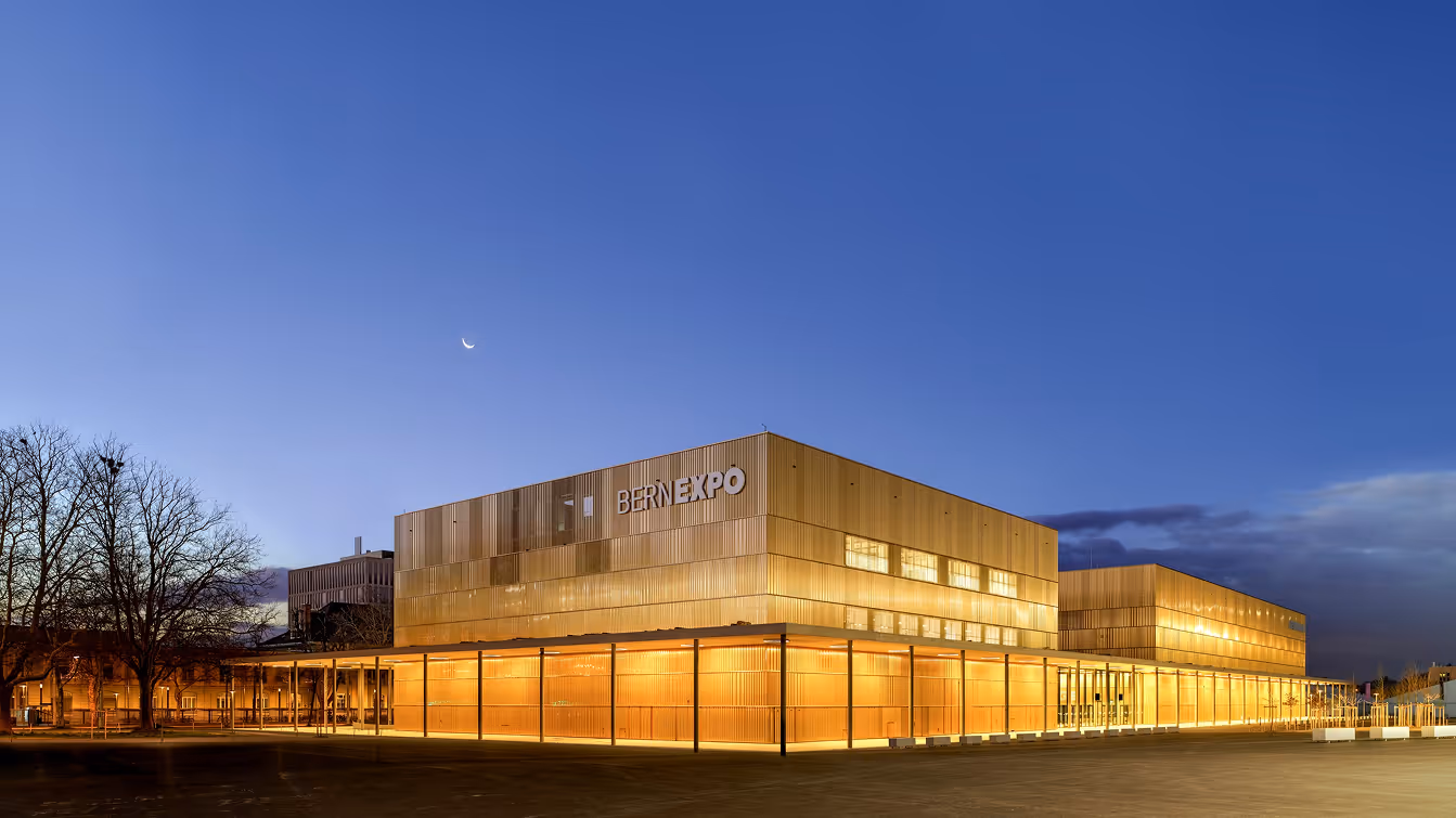 BerExpo convention center building illuminated at dusk under a clear sky with a crescent moon.