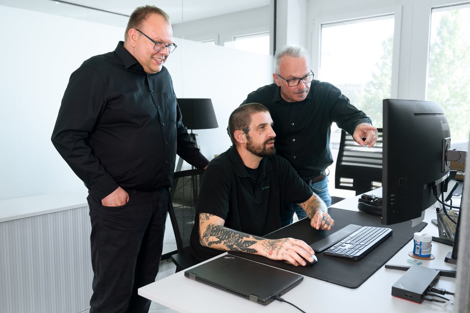 People working in a bright modern office with laptops and tablets at desks and standing.
