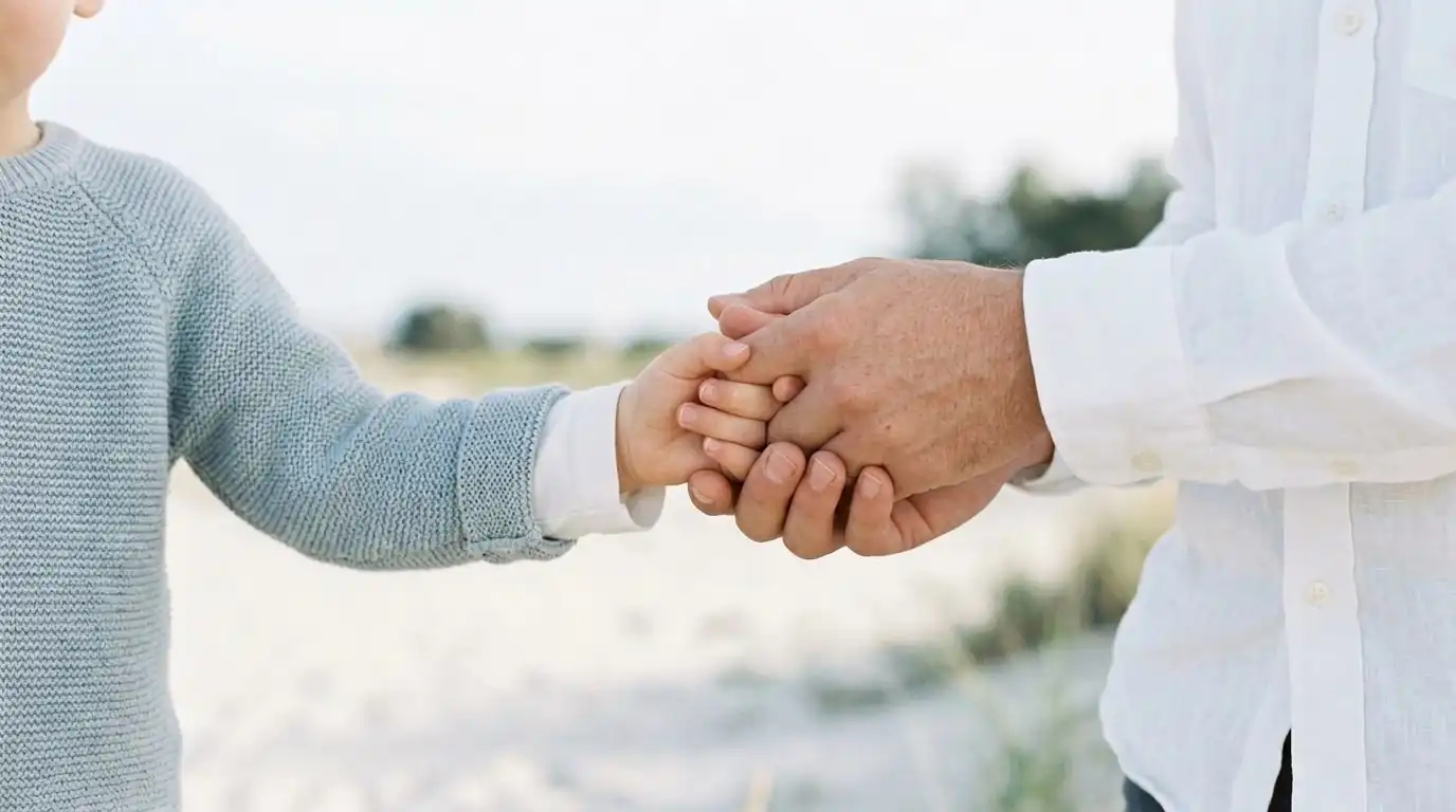 Gentle lifestyle scene of a child holding a parent's hand, soft natural daylight, warm and calm mood, minimal background, focus on hands