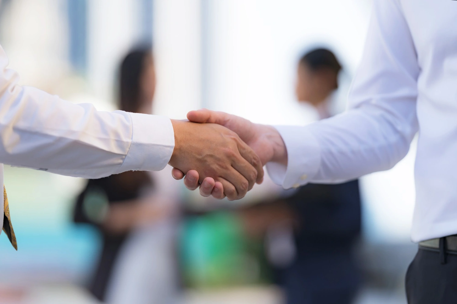 Professional office scene with handshake moment, subtle tension in hands, clean modern workspace,