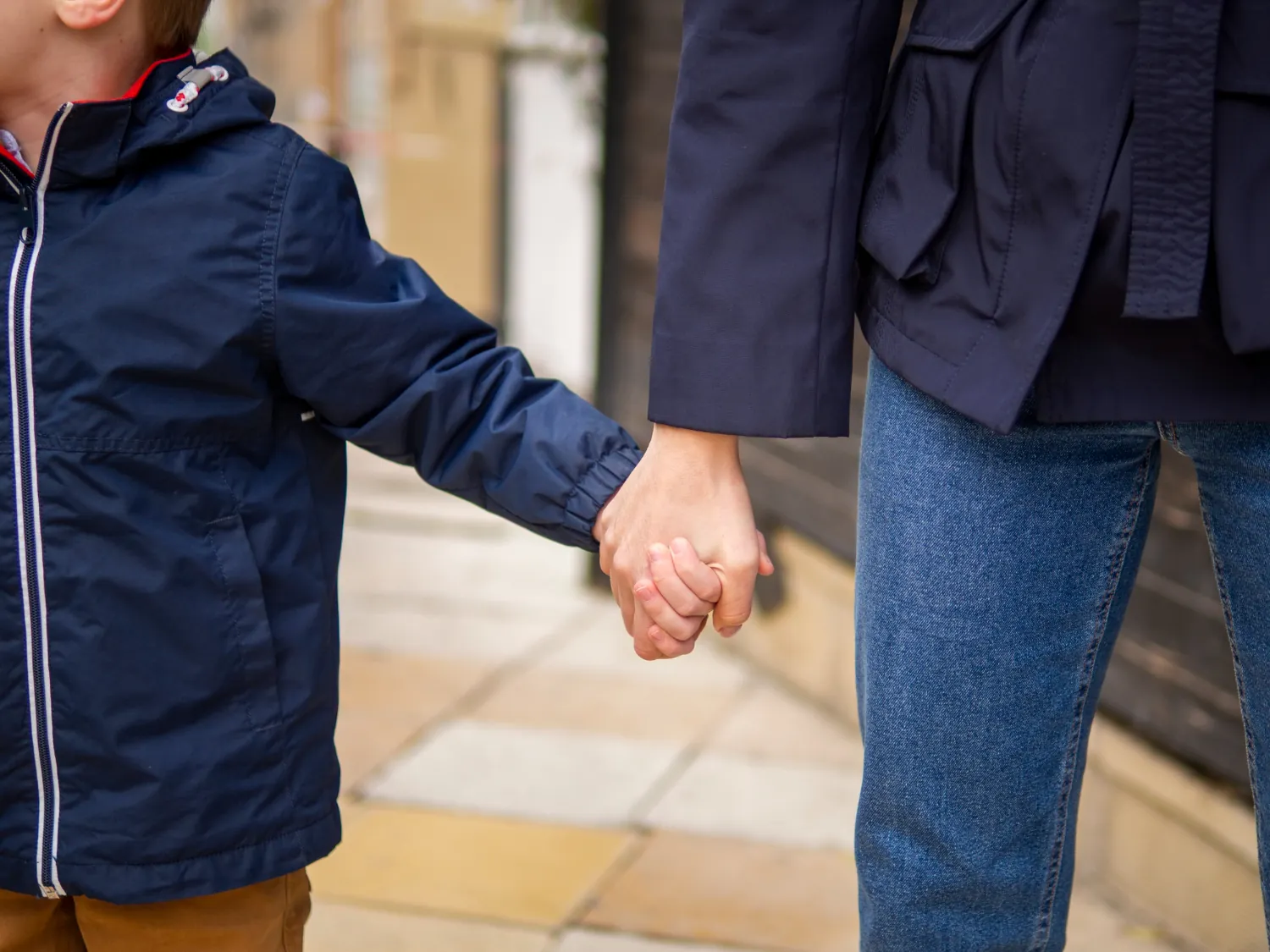 Gentle lifestyle scene of a child holding a parent's hand, warm and calm mood, minimal background, focus on hands