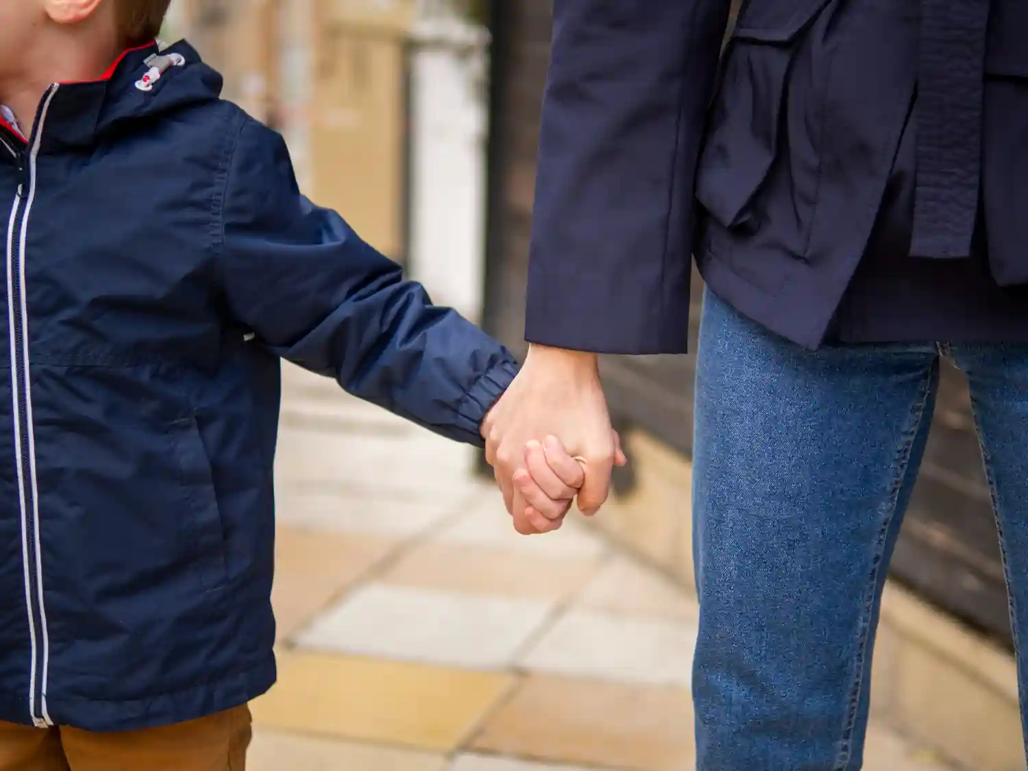 Gentle lifestyle scene of a child holding a parent's hand, warm and calm mood, minimal background, focus on hands