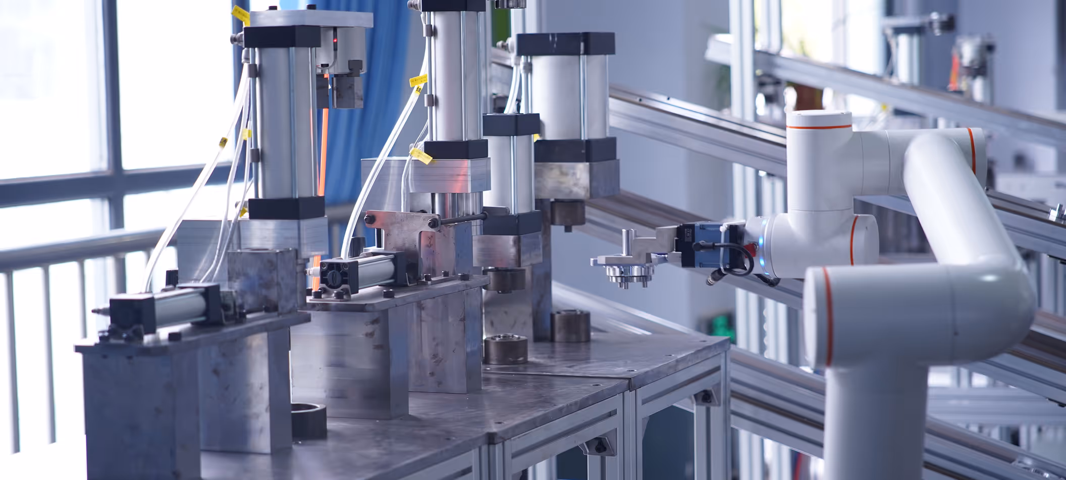 Robotic arm with gripper interacting with automated machinery on a metal workbench in a modern industrial setting.