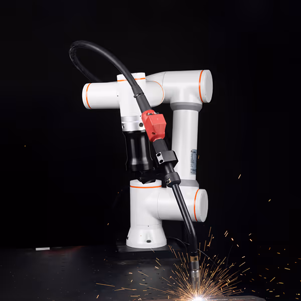 White robotic arm with orange accents performing a welding task with sparks flying.