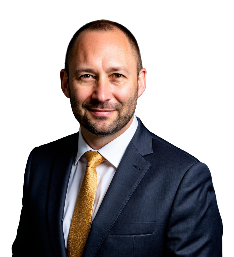 Smiling man with a beard wearing a dark suit, white shirt, and yellow tie against a dark background.