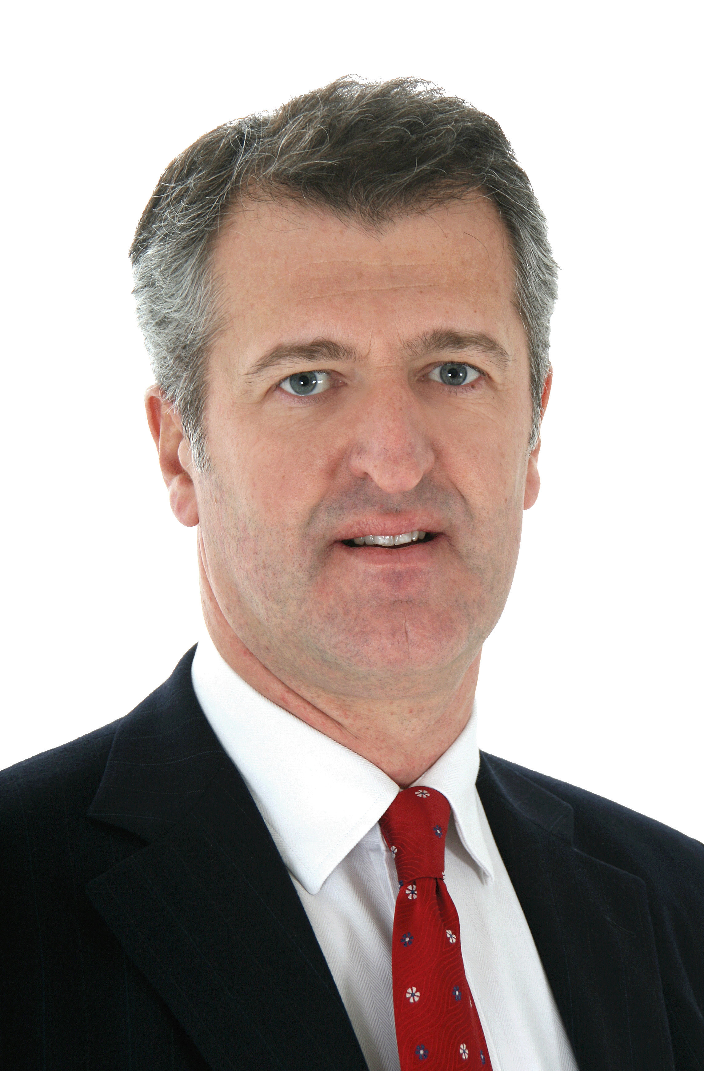 Middle-aged man with gray hair wearing a dark suit, white shirt, and red patterned tie.