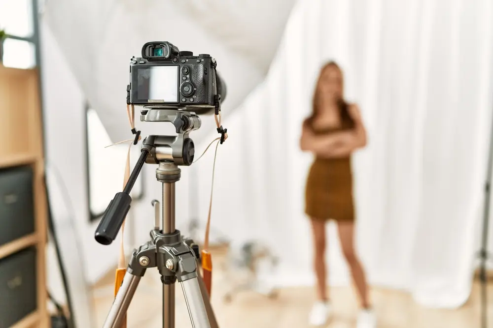Kamera auf einem Stativ fotografiert eine Frau vor weissem Hintergrund
