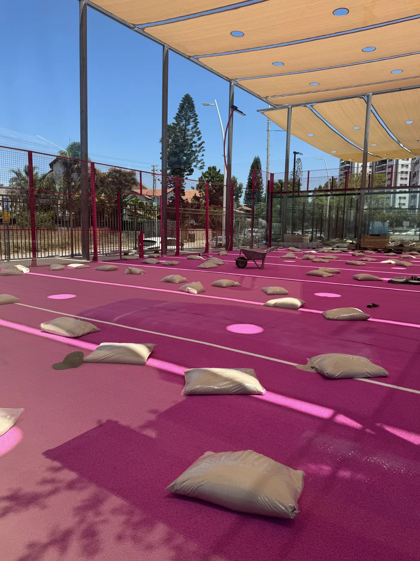 אזור · דשא ורוד שנפרס ושקים על המשטח בזמן העבודות.