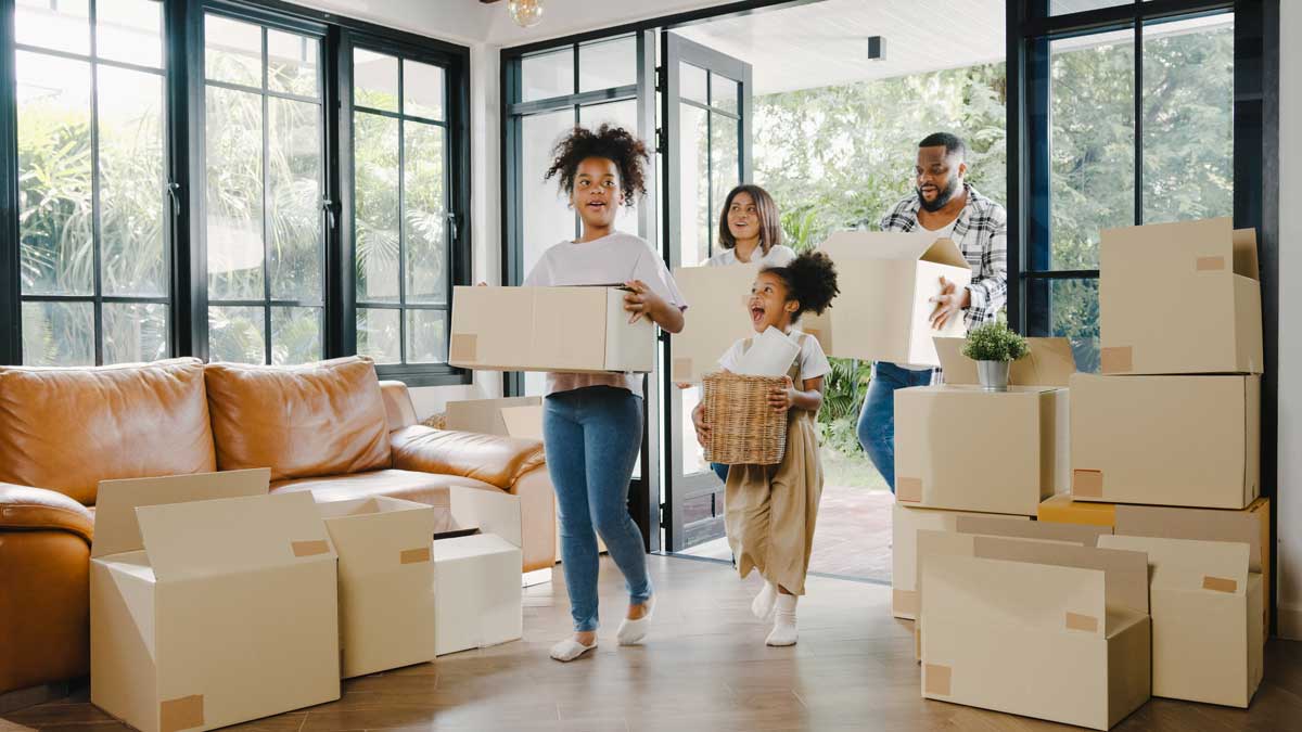 Family unpacking moving boxes in the living room of their first home