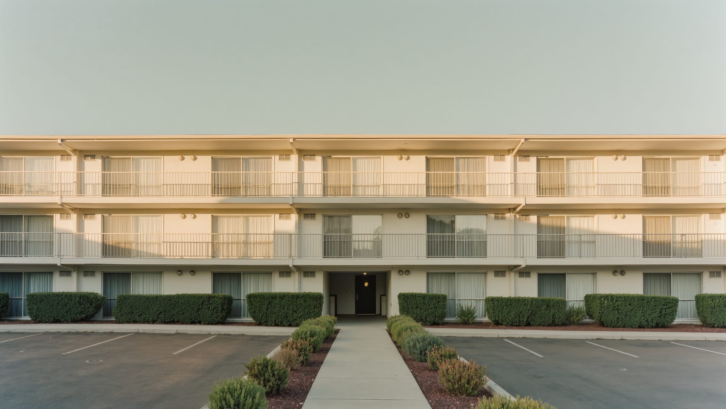 Exterior of a small modern four-unit residential rental building in afternoon light